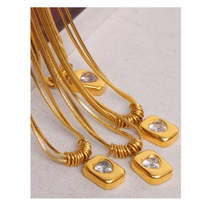 Detailed view of gold rectangle pendants with heart stones on sleek snake chains