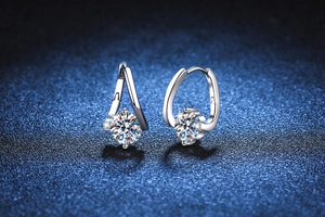 Macro shot of 1ct Moissanite earrings in silver setting on dark textured background