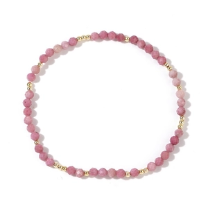 Pink faceted gemstone beaded bracelet with gold spacers on white background