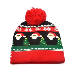 Detail of Christmas knitted hat with Santa Claus, tree patterns and red pom pom