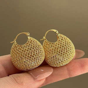 Macro detail of gold-tone woven hollow mesh ball earrings featuring intricate texture