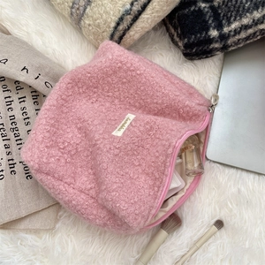 Gedetailleerde weergave van de roze teddy fleece make-uptas met ruime binnenopslag