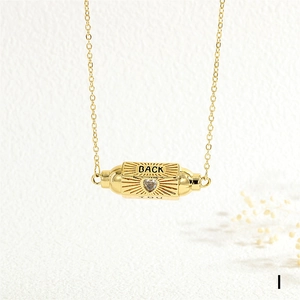 Detail of gold pendant featuring a heart-shaped zircon and BACK YOU engraved text