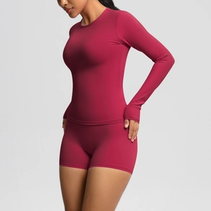 Detail of burgundy long sleeve yoga top with thumbholes and high-waist fitness shorts
