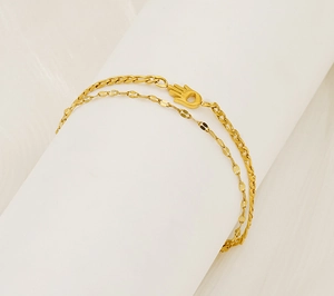 Detailed macro of double-layer gold Hamsa Hand bracelet with flat link chain and beads