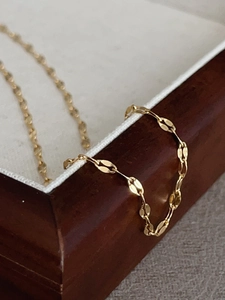 Macro shot of 18k gold plated titanium steel chain necklace on a wooden jewelry box