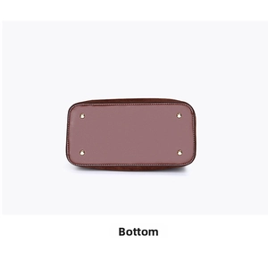 Detail view of the handbag bottom featuring four gold metal protective feet and stitching