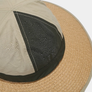 Close-up of waterproof fabric and straw brim showing water droplets on outdoor sun hat