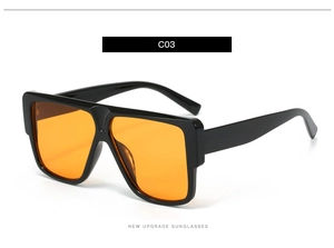 Close-up of oversized square sunglasses with black frame and translucent amber lenses