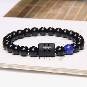 Macro shot of Pisces constellation bead on a black stone bracelet with blue lapis accent