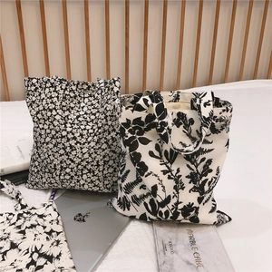 Detail of minimalist black and white floral cotton handbags on a cozy bed setup