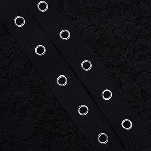 Détail de robe en dentelle noire avec œillets métalliques argentés et laçage raffiné
