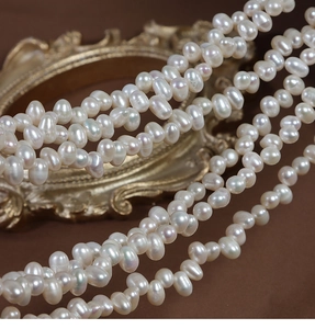 Macro detail of irregular 4-5mm natural white freshwater pearls on vintage gold mirror