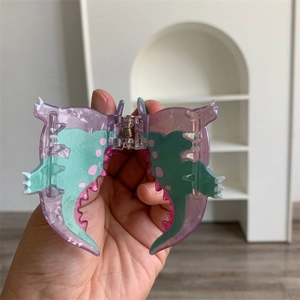 Detailed view of a purple acrylic mini dinosaur hair claw clip with colorful fin patterns
