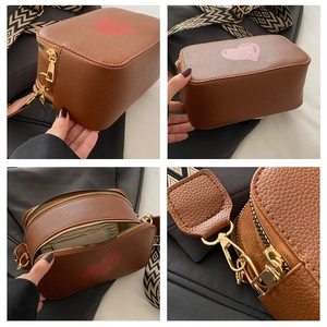 Macro view of brown PU leather bag with heart patterns and wide geometric strap