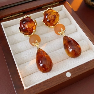 Vintage amber teardrop earrings with three-stage tassel design on velvet jewelry box display