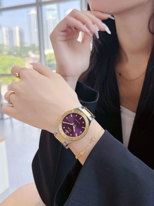 Detail of luxury purple dial watch with gold-silver strap and planet logo on wrist