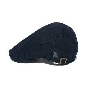 Detail of navy cotton flat cap showing adjustable bronze metal buckle and stitching