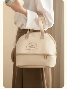 Woman carrying a beige double-layer insulated lunch bag with wide webbed handles