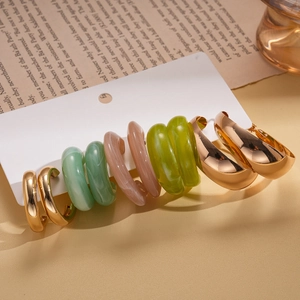 Set of 5 pairs of gold-plated metal and acrylic resin hoop earrings on a vintage display