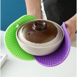 Round silicone honeycomb heat resistant mats in green and purple used with a pot