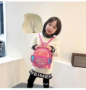 Detail of pink sequin backpack featuring heart patch and holographic wings for girls