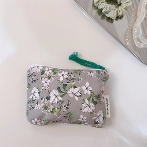 Flat lay of a floral cotton coin purse with green pull cord and decorative accessories