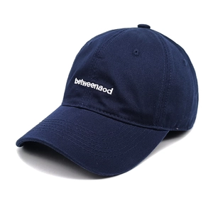 Detail view of deep blue cotton baseball cap with white betweenaod letter embroidery
