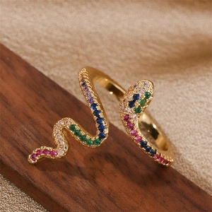 Bague serpent dorée avec cristaux de zircon colorés sur support en bois sombre