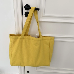 Detailed close-up of a lemon yellow large canvas tote bag hanging on a white door handle
