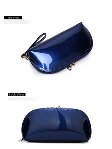 Macro view of shell-shaped blue patent leather bag with heart-shaped zipper and wrist strap