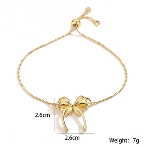 Detail showing 2.6cm golden bow pendant and adjustable drawstring chain on gold bracelet
