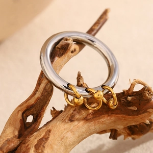 Detail of creative stainless steel ring with 18K gold tassels on a natural wood branch