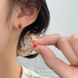 Sweet red strawberry stud earrings with green leaves shown on ear for size reference