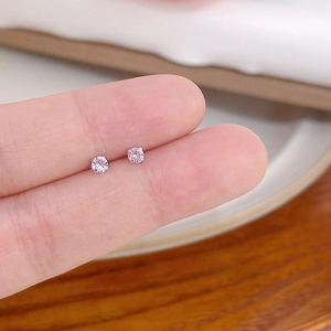 Close-up of mini pink zircon stud earrings with four-prong setting held by fingers