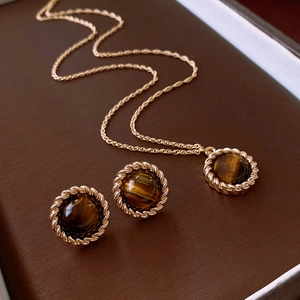 Detail of vintage gold jewelry set featuring round tiger eye stones with rope borders