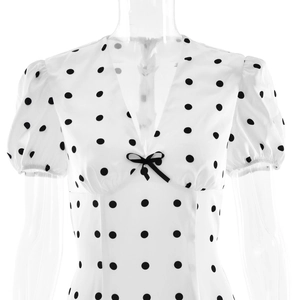 Detail of V-neckline with black bow accent on a white polka dot summer dress