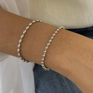 Detail of silver stainless steel bead and oval link bracelets on a female wrist