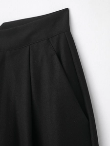 Gros plan sur la texture du tissu sergé noir et les détails des poches du pantalon femme