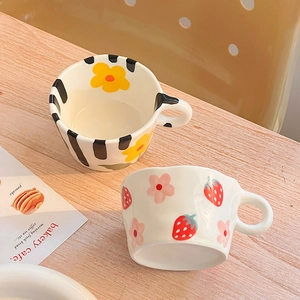 Top view of two ceramic mugs with wide handles and hand-painted floral and stripe patterns