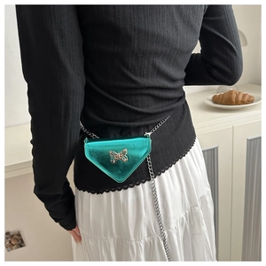 Détail du sac bandoulière triangle vert métallisé avec chaîne argentée porté par une femme