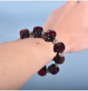 Macro shot of punk style skull bracelet with dark red resin beads and silver spacers