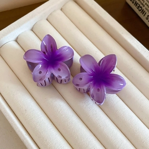 Close-up of two purple gradient sunflower hair claws on a white jewelry display pad