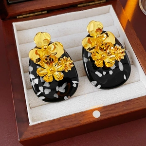 Detail view of vintage gold flower earrings with polka dot oval base in a wooden jewelry box