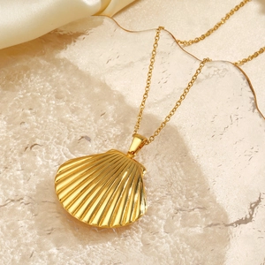 Golden stainless steel seashell necklace displayed on textured tray with silk fabric