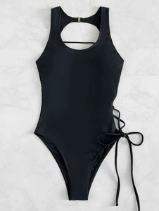 Detail of black one-piece swimsuit featuring side cutout design and delicate ribbon tie