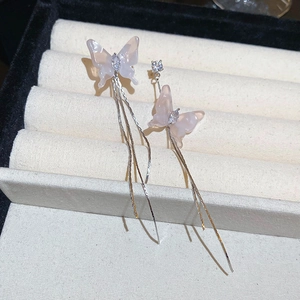 Detail of pink resin butterfly earrings with sparkling zircons and long silver tassels