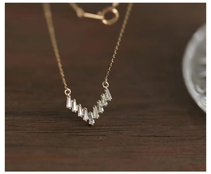 Detailed close-up of 925 silver V-shaped necklace with baguette-cut zircons and gold finish