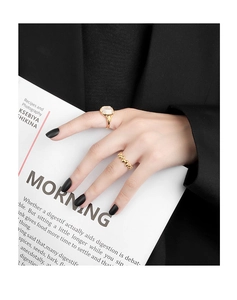 Detail of gold bubble ring and rectangle gemstone ring on a model with a magazine