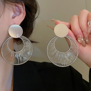 Detailed macro view of geometric silver earrings with intricate wire-wrapped hollow circle